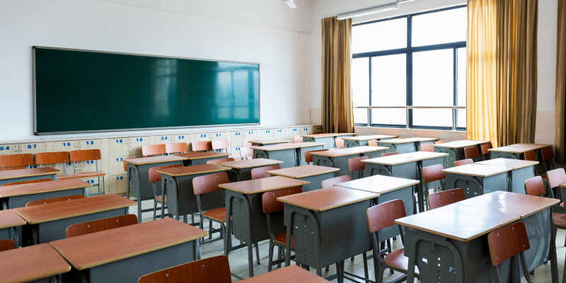 Empty classroom with chairs, desks and chalkboard.