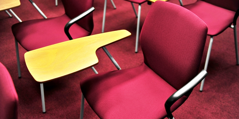 Chairs with writing pads - a type of school chair arranged in a classroom.